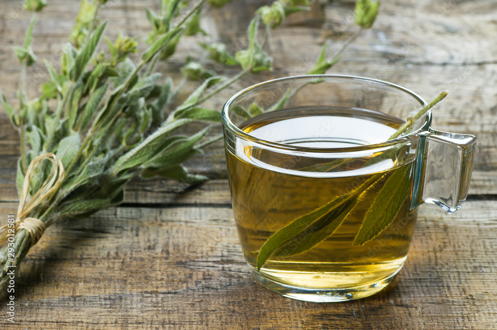 Glass cup of herbal sage tea with dried sage leaves on wooden rustic background. Herbal tea hot drink concept, Salvia officinalis Glass cup of herbal sage tea with dried sage leaves on wooden rustic background. Herbal tea hot drink concept, Salvia officinalis
