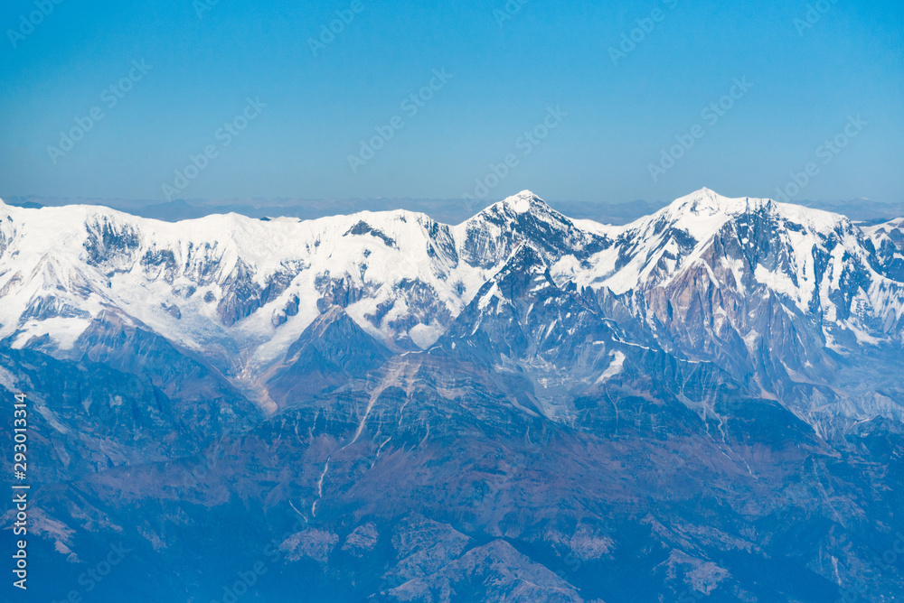 Aerial view from a plane over Himalaya mountains on a bright sunny morning.