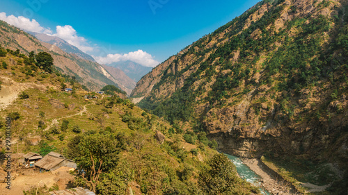 River flows trough rocky valley in Himalaya mountains in Nepal during sunny summer day. 
