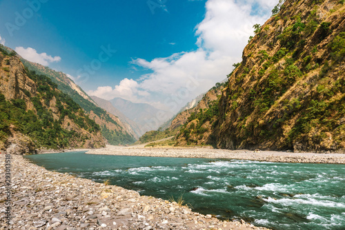 River flows trough rocky valley in Himalaya mountains in Nepal during sunny summer day.  © valdisskudre