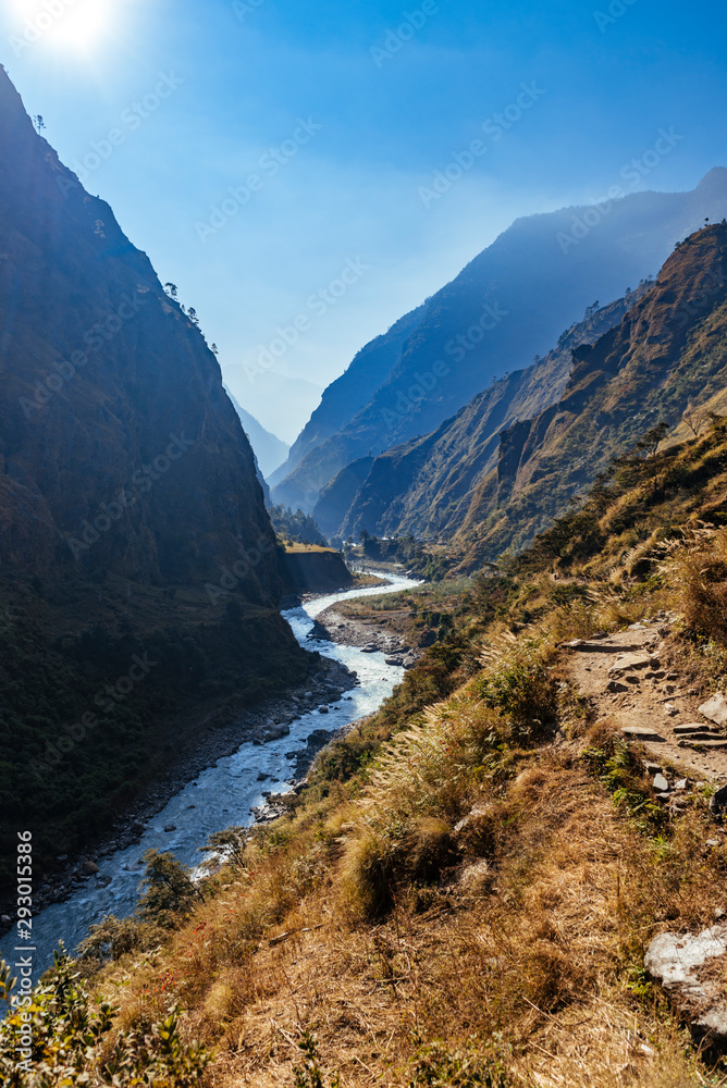 River flows trough rocky valley in Himalaya mountains in Nepal during sunny summer day.	