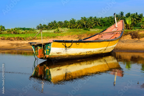 Local colorful fishing boat anchored in the shallow water photo