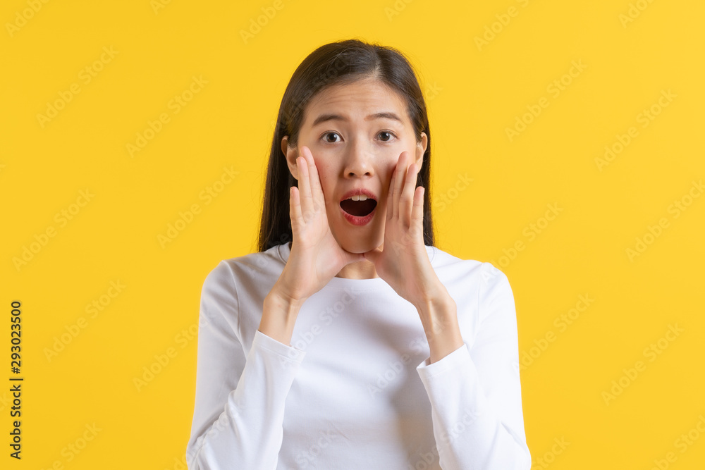 asian teenager in white casual shirt telling gossip news isolated on yellow background in studio. asian teenager in white casual shirt telling gossip news isolated on yellow background in studio.