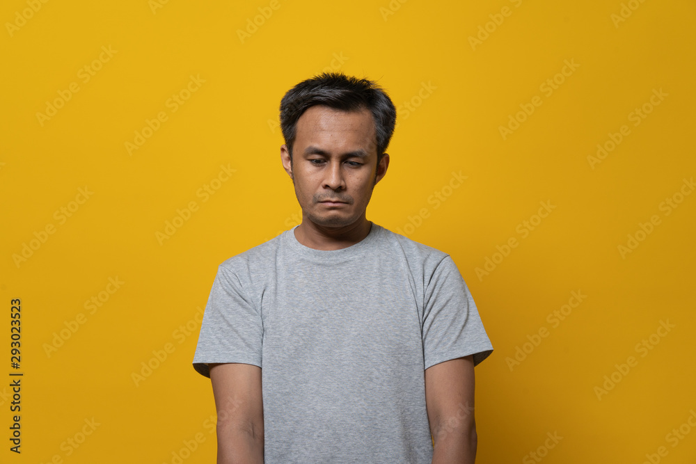 Depressed asian young man face down feeling failure. Shot in studio isolated on yellow background. Depressed asian young man face down feeling failure. Shot in studio isolated on yellow background.