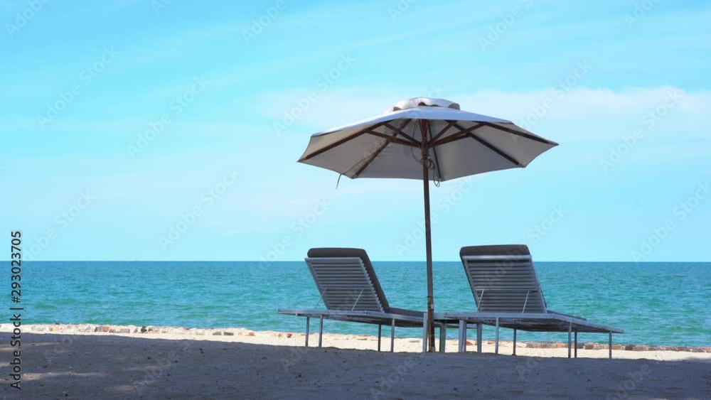 Two lounge chairs and an umbrella on a sunny beach, sea view background. Static. Two lounge chairs and an umbrella on a sunny beach, sea view background. Static.
