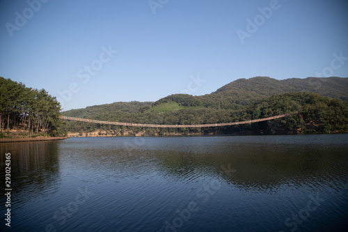 Suspension bridge connected to the mountain across the lake © jeagun