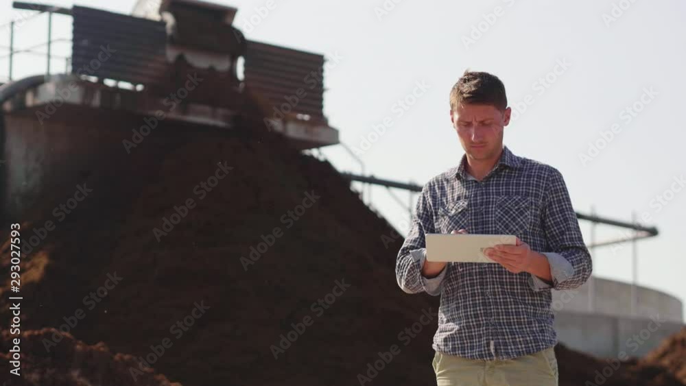 Slow motion of an young agronomist is using advanced technology with a tablet for controlling a quality of an organic cow manure compost used for agricultural soil cultivation and for biogas. Slow motion of an young agronomist is using advanced technology with a tablet for controlling a quality of an organic cow manure compost used for agricultural soil cultivation and for biogas.
