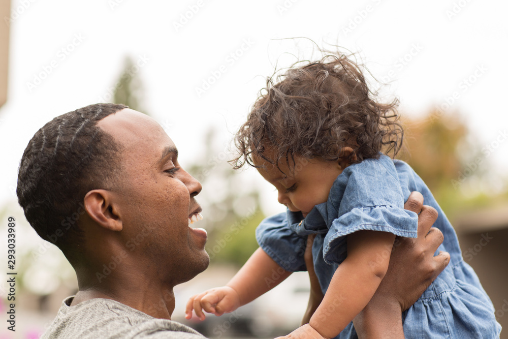 Fototapeta premium Father holding his little girl. Mixed race family.