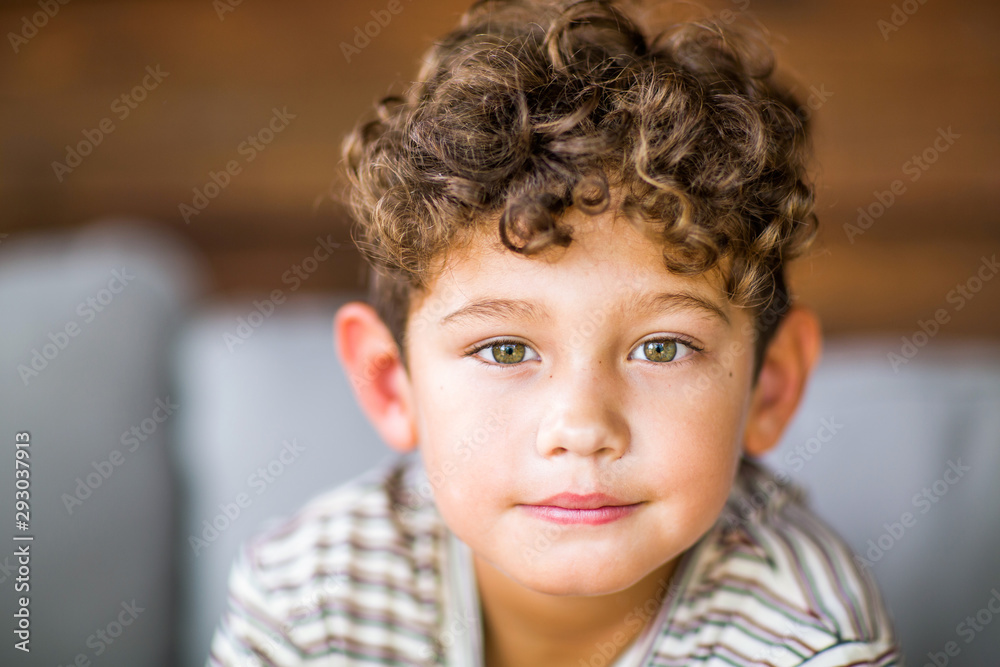 Handsome young boy with curly hair smiling. - obrazy, fototapety, plakaty 