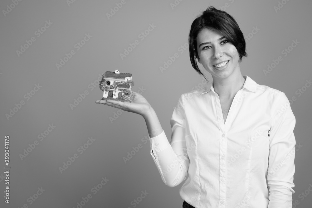 Portrait of young beautiful real estate agent holding house shot in black and white Portrait of young beautiful real estate agent holding house shot in black and white