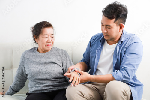 Fototapeta Naklejka Na Ścianę i Meble -  Asian senior woman mother and young man son in blue shirt massage his mother in living room