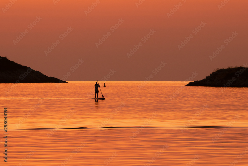 stand up paddling at sunset as trendy sport concept