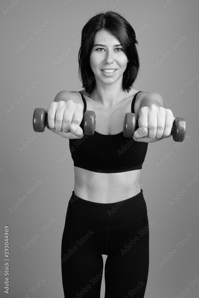 Young beautiful woman ready for gym against gray background Young beautiful woman ready for gym against gray background
