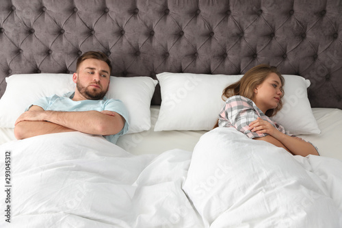 Young couple with relationship problems in bed at home