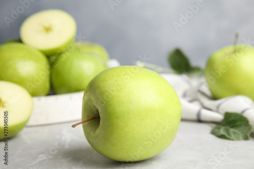 Fresh ripe green apples on grey stone table against blue background, space for text