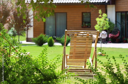 Wooden deck chair in beautiful garden on sunny day