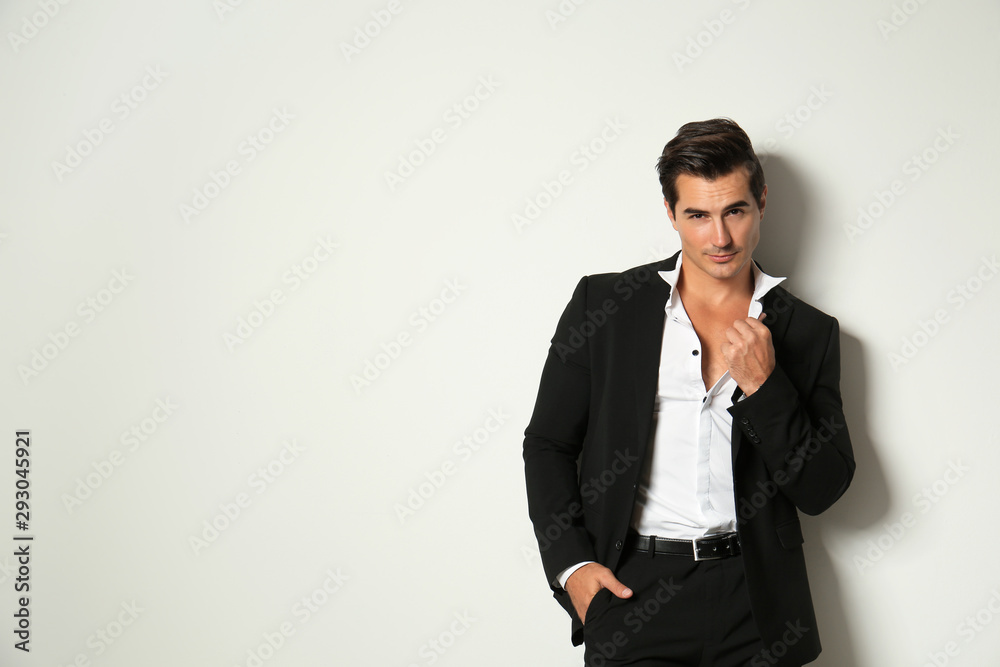 Handsome young man in elegant suit on light beige background. Space for text Handsome young man in elegant suit on light beige background. Space for text