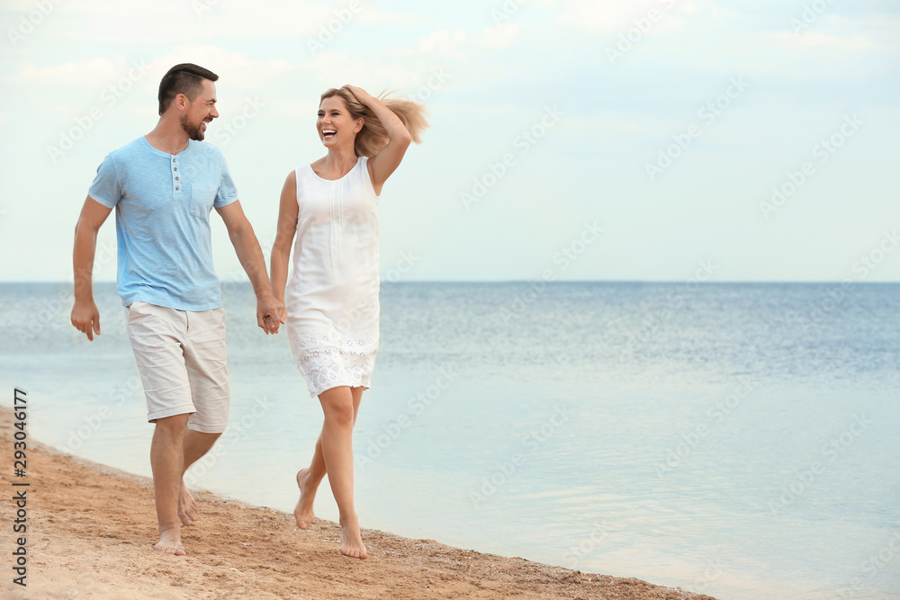 Happy romantic couple running together on beach, space for text Happy romantic couple running together on beach, space for text