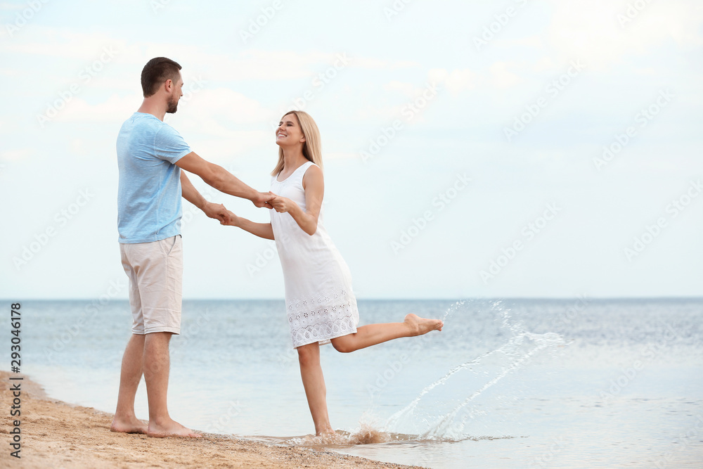 Happy romantic couple dancing on beach, space for text