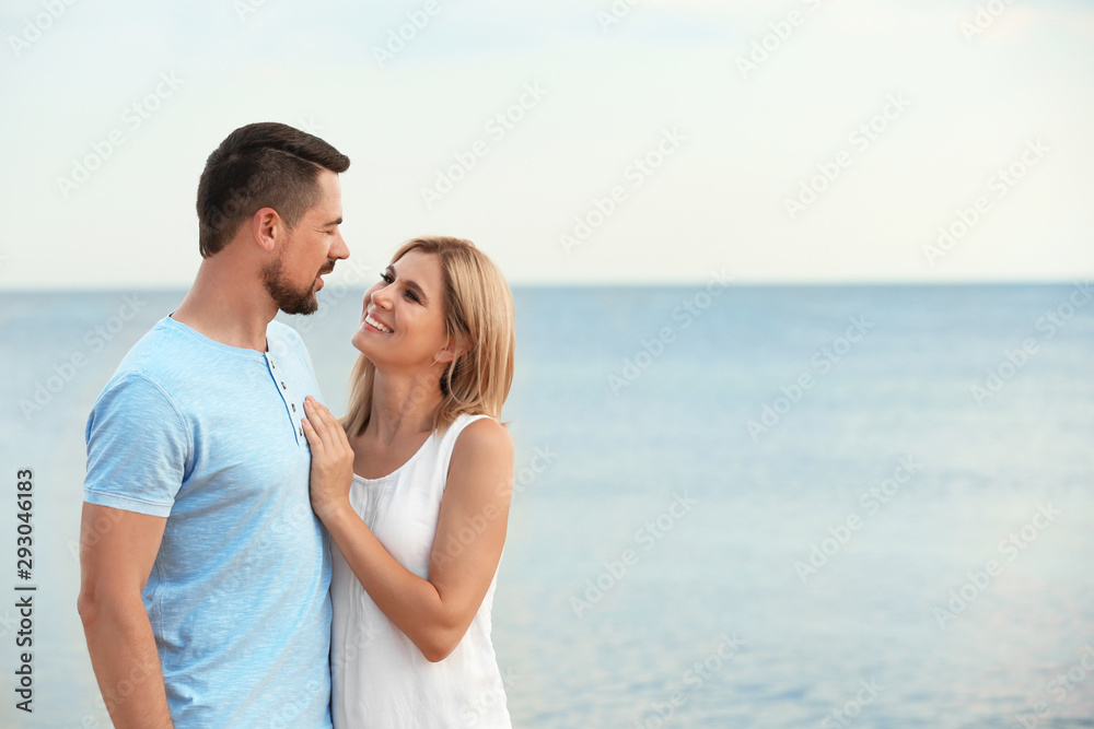 Happy romantic couple spending time together on beach, space for text