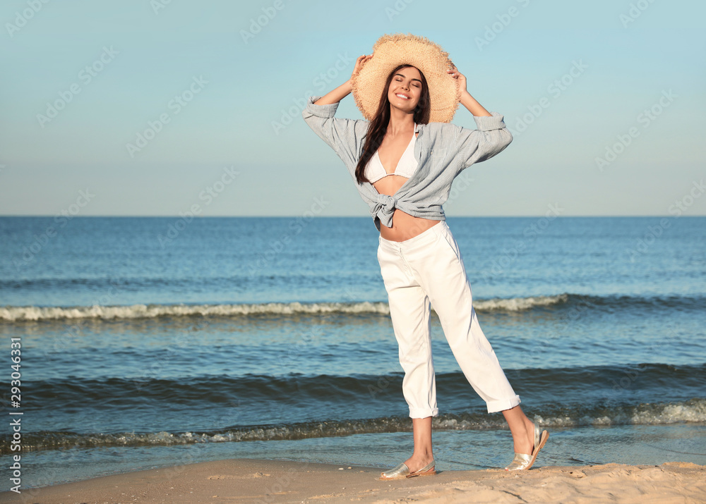 Beautiful young woman in straw hat on beach