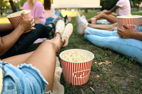 Young people with popcorn watching movie in open air cinema, closeup Fototapeta