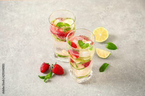 Tasty refreshing drink with strawberry on light grey table