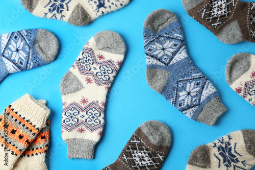 Different knitted socks on light blue background, flat lay. Winter clothes