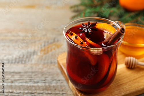 Glass cup of tasty mulled wine on wooden table. Space for text