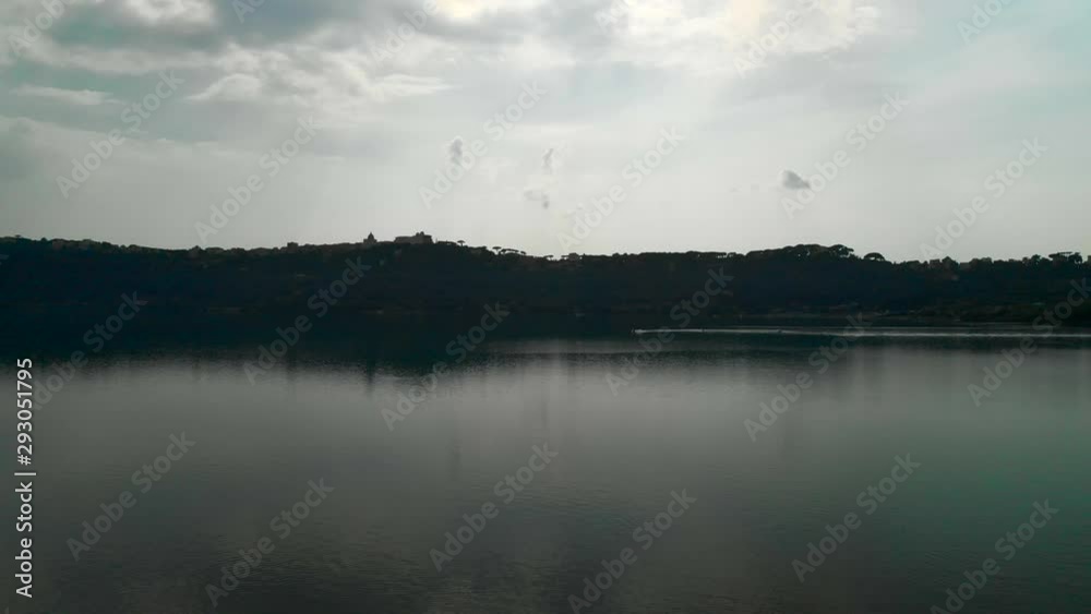 AERIAL DOLLY IN: Drone flying over Lake Albano in Rome, Italy with stunning trees' reflection on the water and a papal summer residence in the distance AERIAL DOLLY IN: Drone flying over Lake Albano in Rome, Italy with stunning trees' reflection on the water and a papal summer residence in the distance