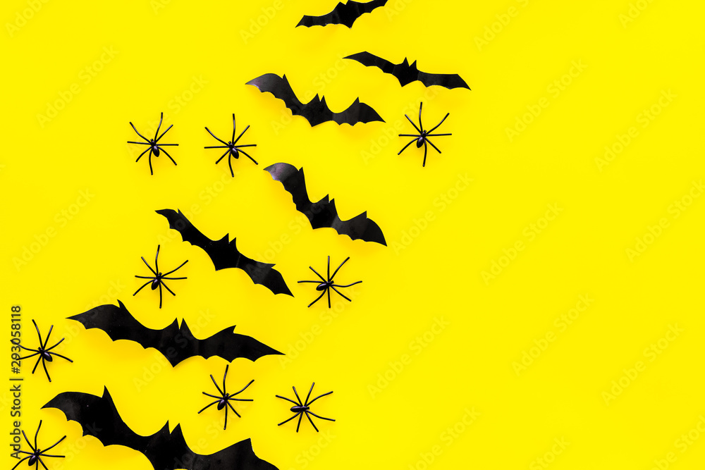 Fototapeta premium Stylish Halloween design. Bats and spiders on yellow background top view copy space