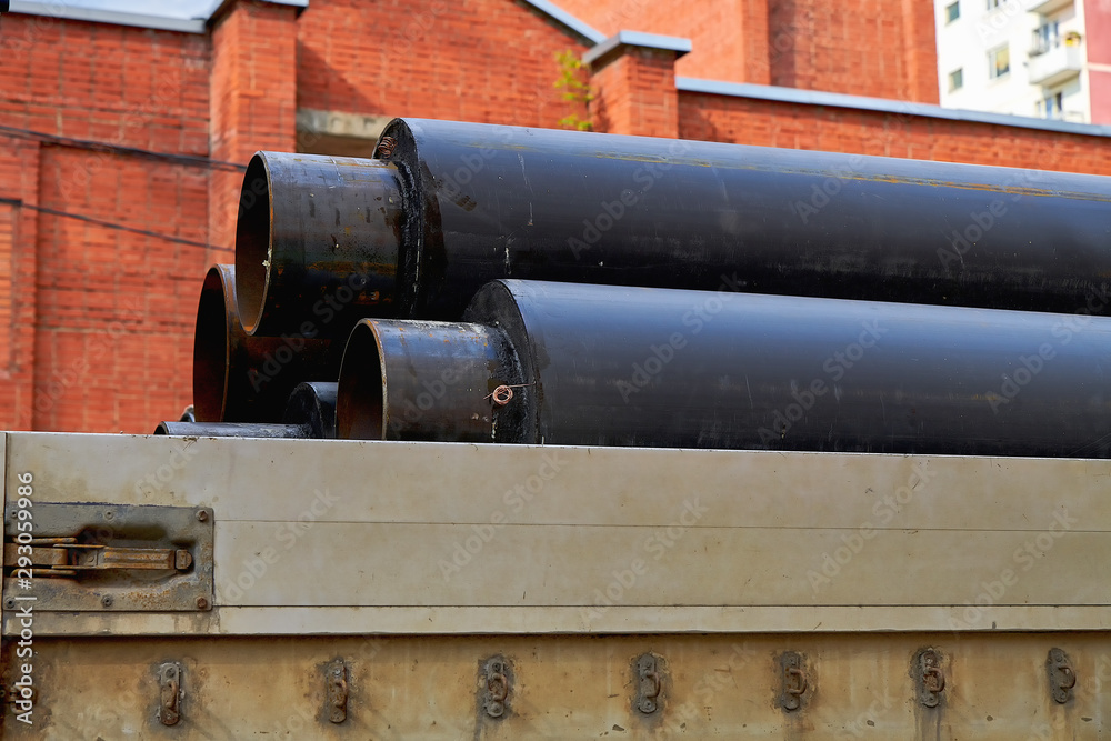 Large black pipes with insulation in the back of a truck close-up. Delivery of building materials to the construction site.