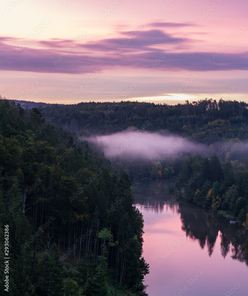 Close up to Vltava river from vantage point with fog and trees at sunrise, blue hour