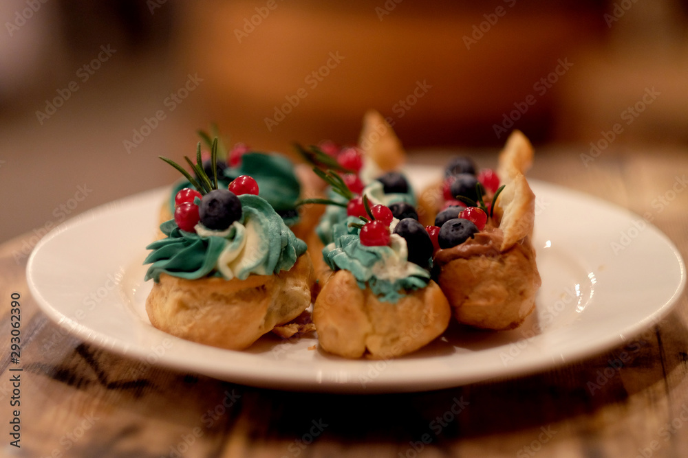 eclairs decorated with fresh berries on a white plate, handmade, culinary theme, close up