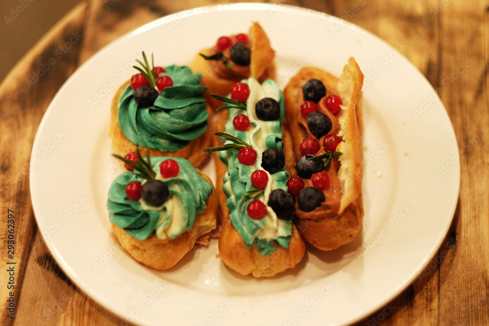 eclairs decorated with fresh berries on a white plate, handmade, culinary theme, close up eclairs decorated with fresh berries on a white plate, handmade, culinary theme, close up