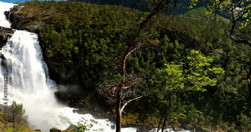 Kinsarvik, Hordaland, Norway. Waterfall Nyastolfossen In Hardangervidda Mountain Plateau. Nyastolsfossen in Spring Sunny Day. Height Of 115 m. Famous Landmark And Popular Destination. Panorama Kinsarvik, Hordaland, Norway. Waterfall Nyastolfossen In Hardangervidda Mountain Plateau. Nyastolsfossen in Spring Sunny Day. Height Of 115 m. Famous Landmark And Popular Destination. Panorama