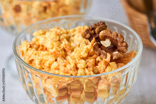Rice salad with carrots, cheese and walnuts in a glass bowl