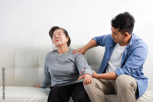 Fototapeta Naklejka Na Ścianę i Meble -  Asian senior woman mother and young man son in blue shirt massage his mother in living room