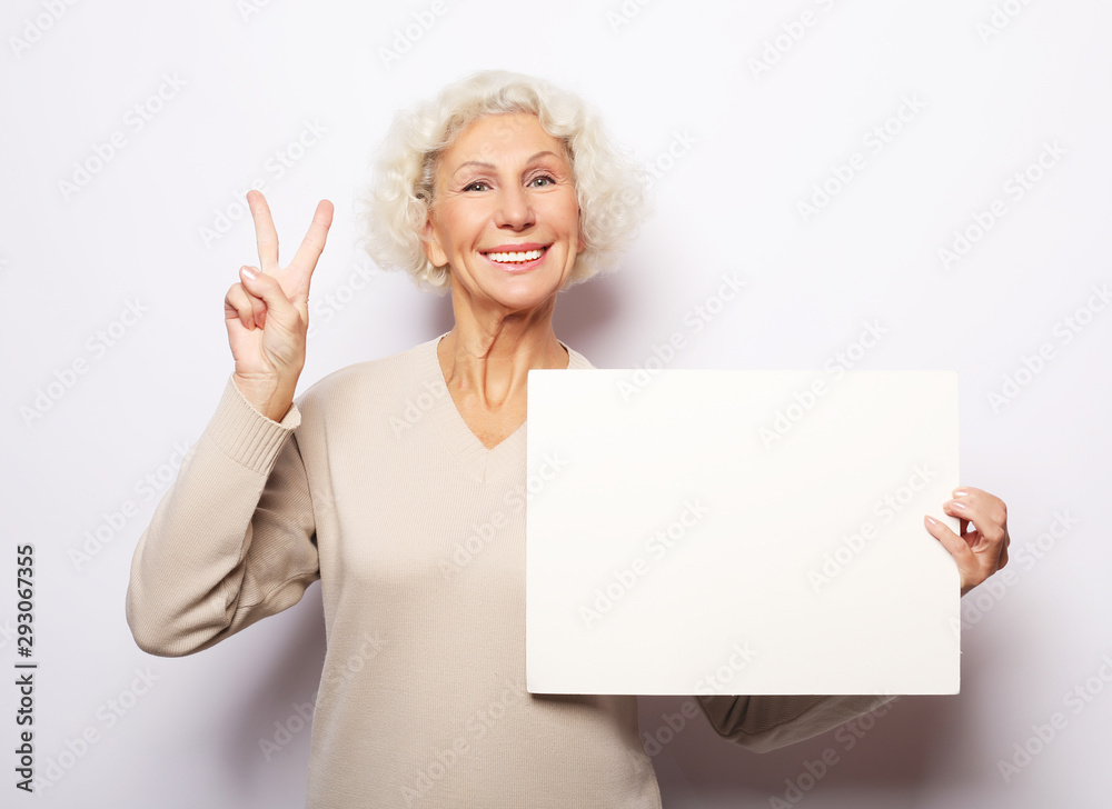 Aged woman with blank advertising board or copy space. Portrait of handsome expressive grandmother. Aged woman with blank advertising board or copy space. Portrait of handsome expressive grandmother.