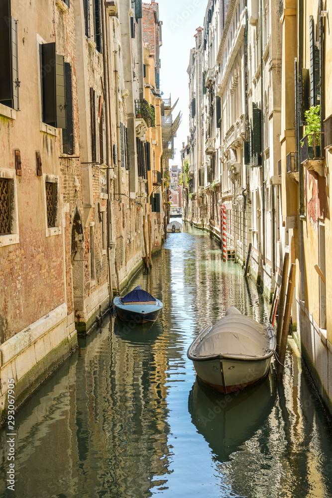 Parked boats in small side canal in city of Venice, Italy
