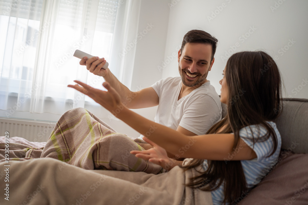 Young couple is watching tv in their bedroom.