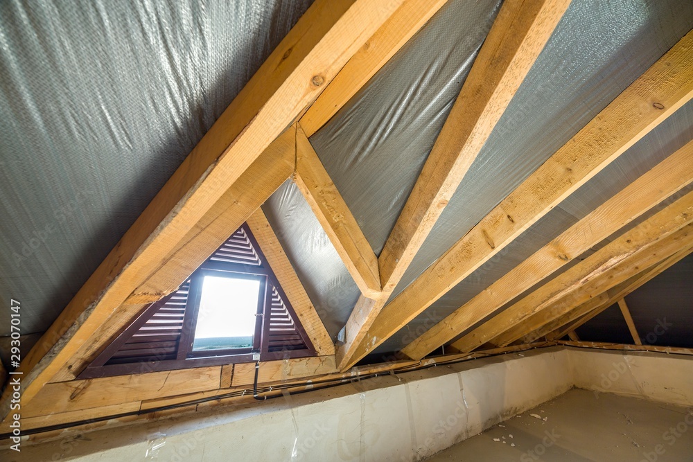 Fototapeta premium Attic of a building with wooden beams of a roof structure and a small window.