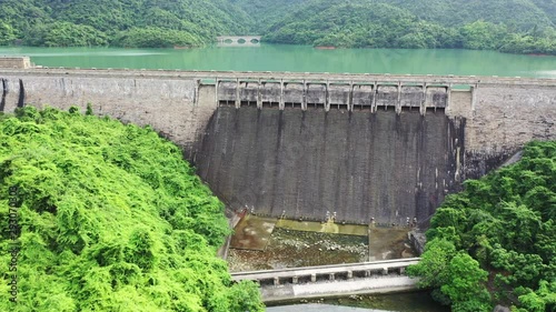 Aerial video of water dam and bridge at reservoir with beautiful mountains and trees photo