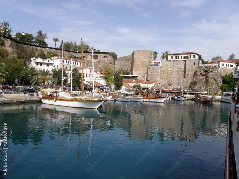 Sea Bay with blue water and white boats along the pier on the background of the stone walls of the ancient fortress