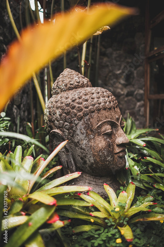 Stone Buddha head close-up. Handmade carved Buddha statue in balinese garden as decoration.