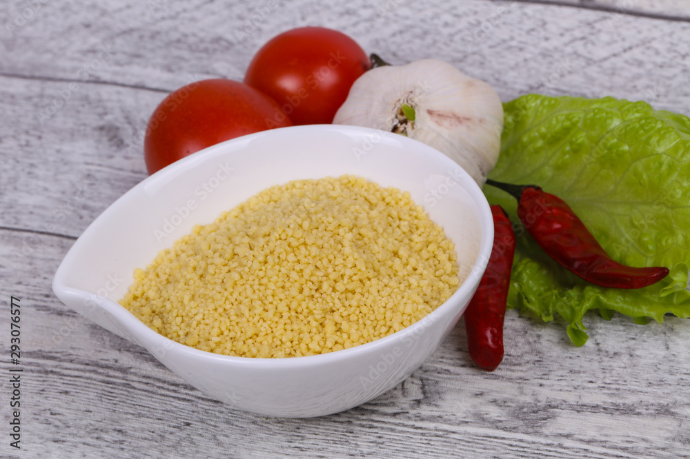 Raw couscous in the bowl served salad leaves, tomato and pepper Raw couscous in the bowl served salad leaves, tomato and pepper