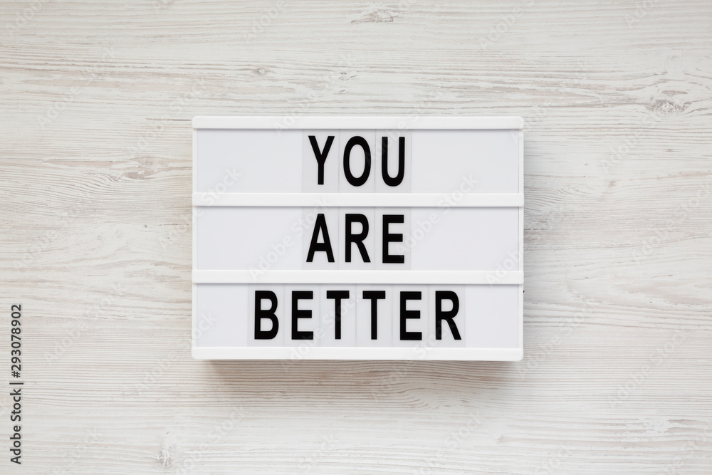 'You are better' words on a lightbox over white wooden background, top view. Overhead, from above. Flat lay. 'You are better' words on a lightbox over white wooden background, top view. Overhead, from above. Flat lay.