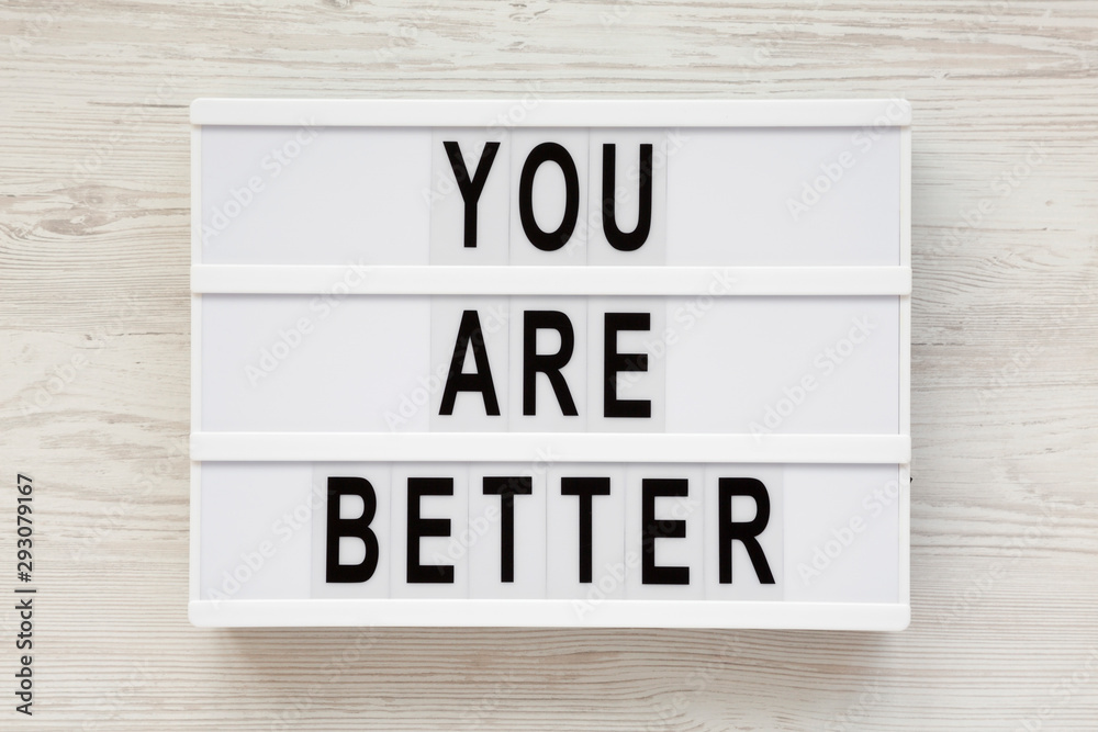 'You are better' words on a modern board over white wooden background, top view. Overhead, from above. Flat lay. 'You are better' words on a modern board over white wooden background, top view. Overhead, from above. Flat lay.