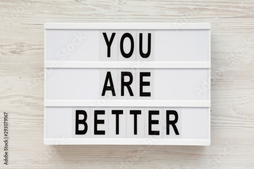 'You are better' words on a modern board over white wooden background, top view. Overhead, from above. Flat lay.