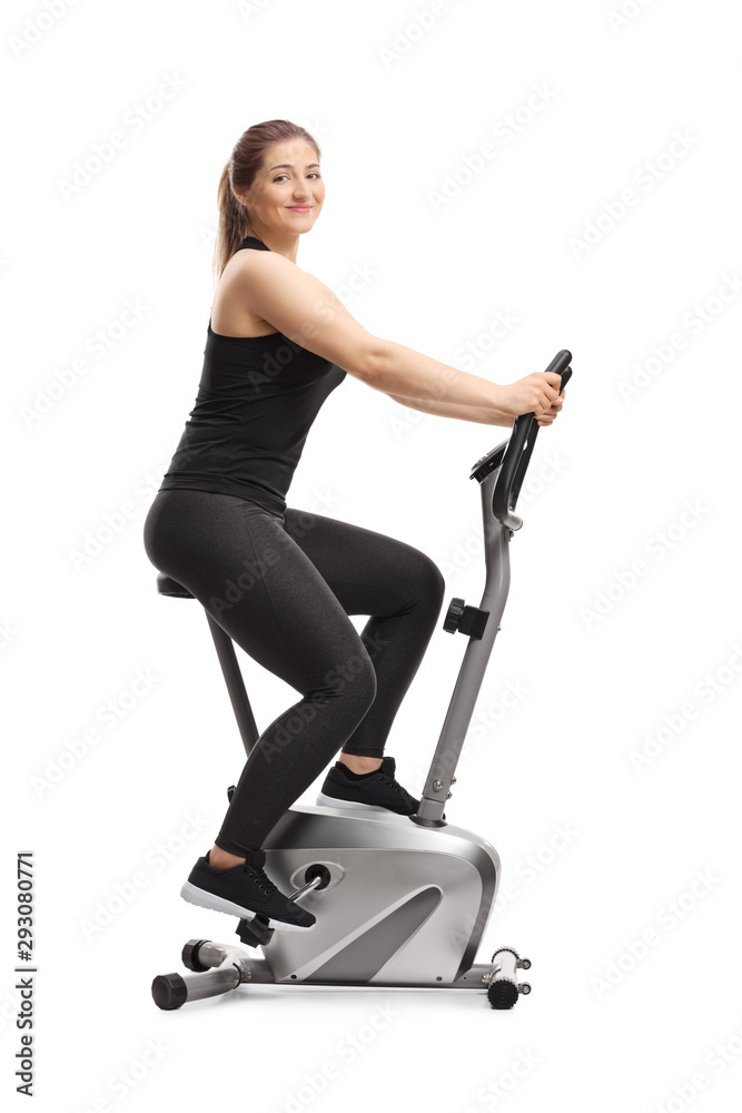 Young woman riding a stationary bike and smiling at the camera Young woman riding a stationary bike and smiling at the camera